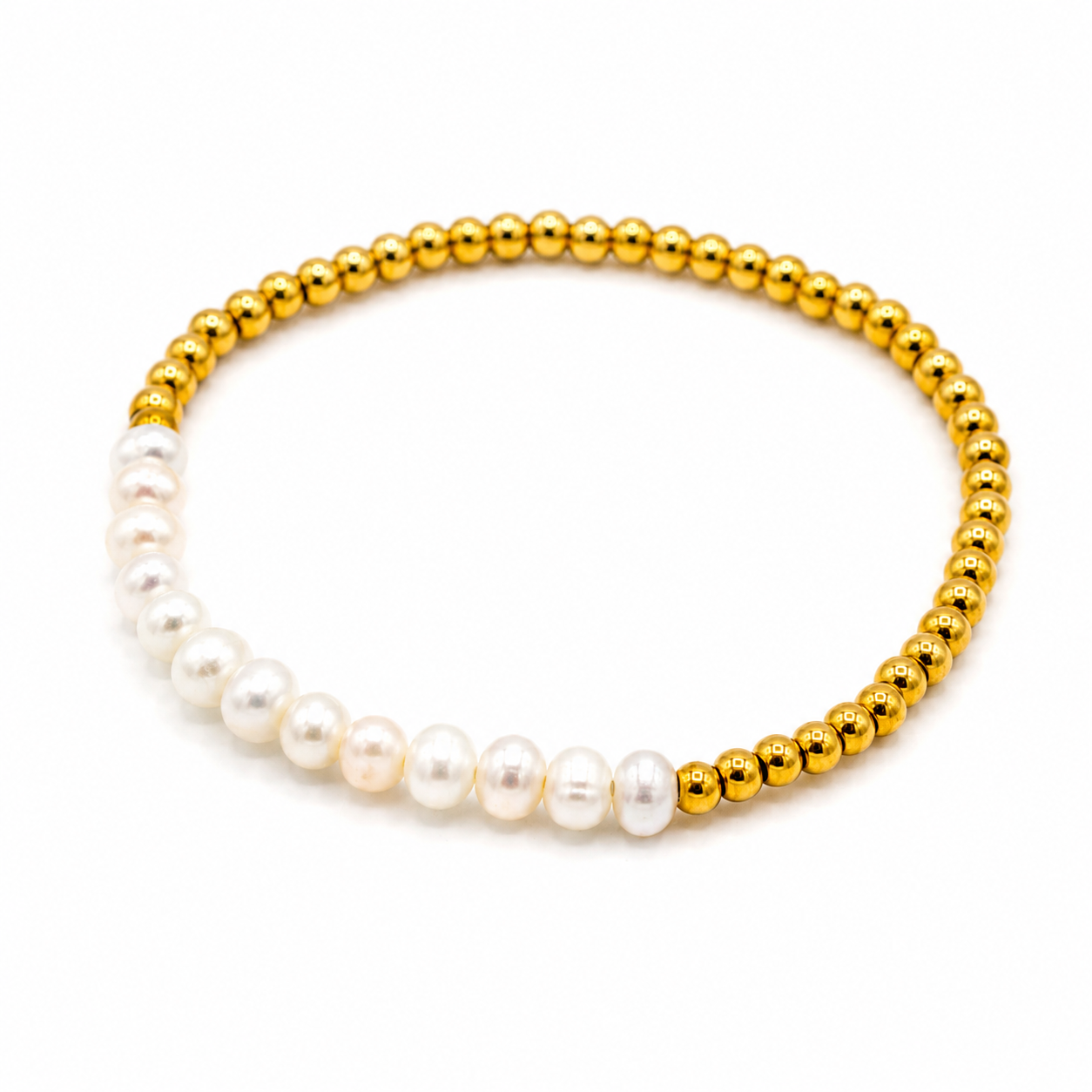A beaded stretch bracelet featuring a half-white pearl section and a half-polished gold bead section