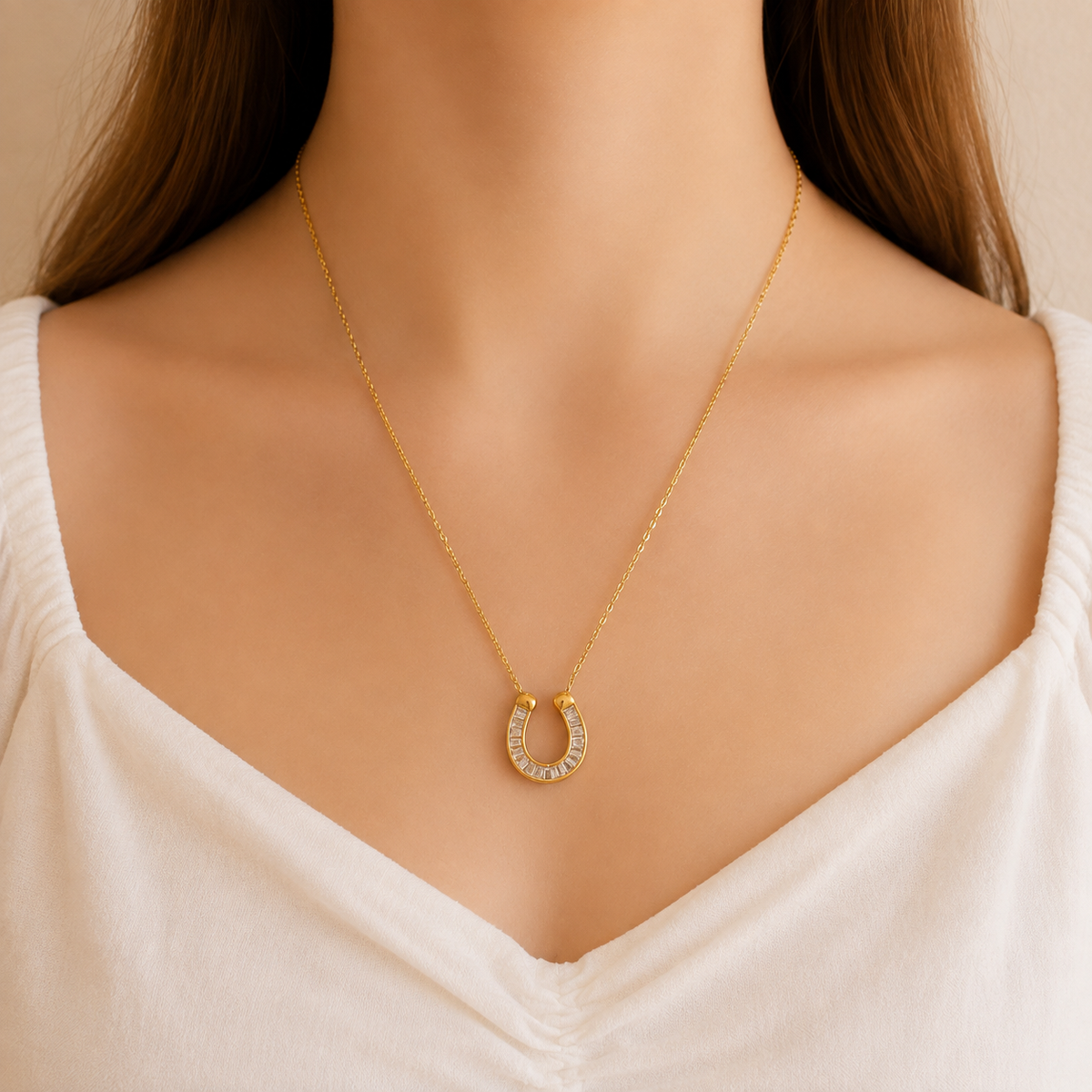 A gold horseshoe pendant necklace with small clear stones
