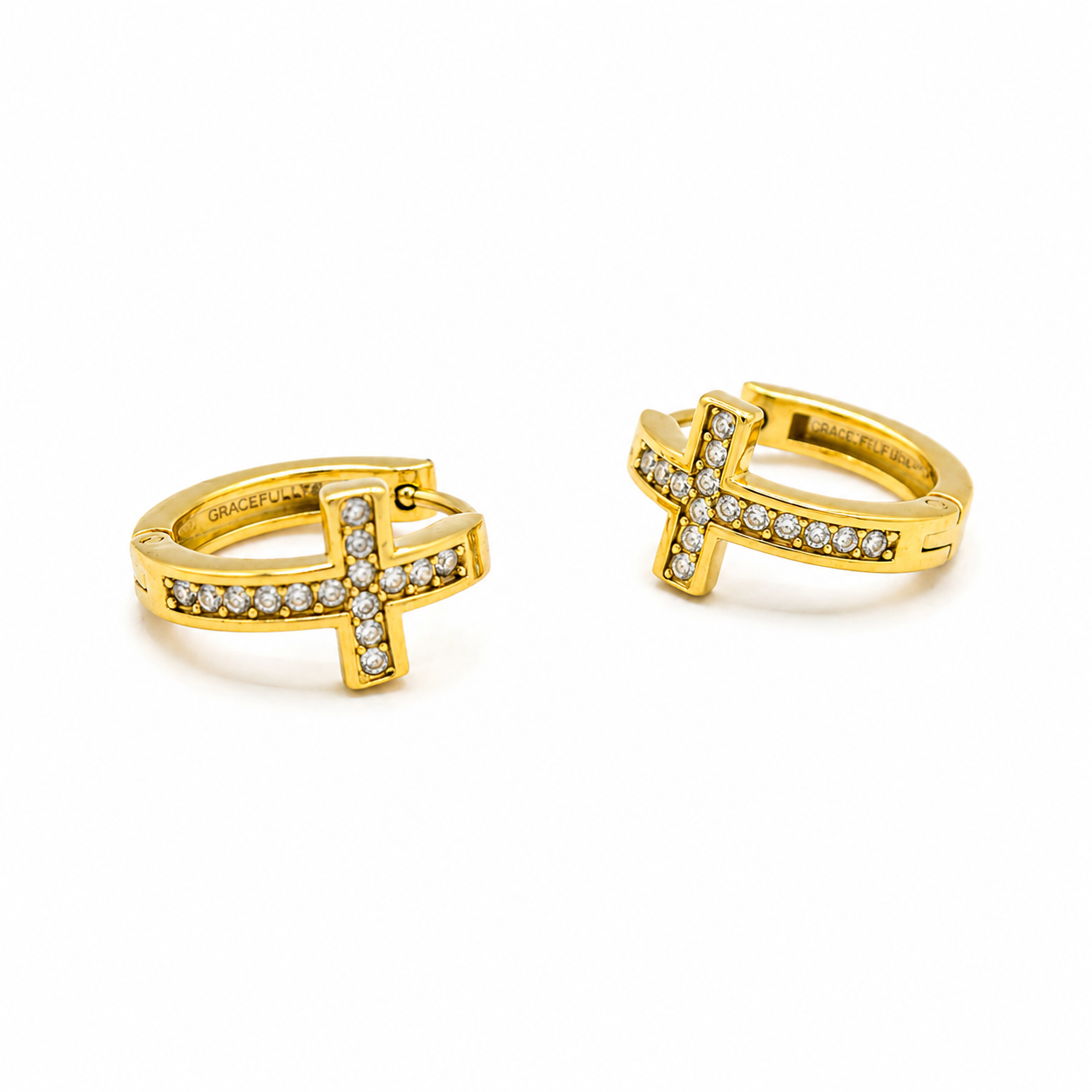 A pair of gold huggie hoop earrings with a cross design, embellished with small clear pavé stones