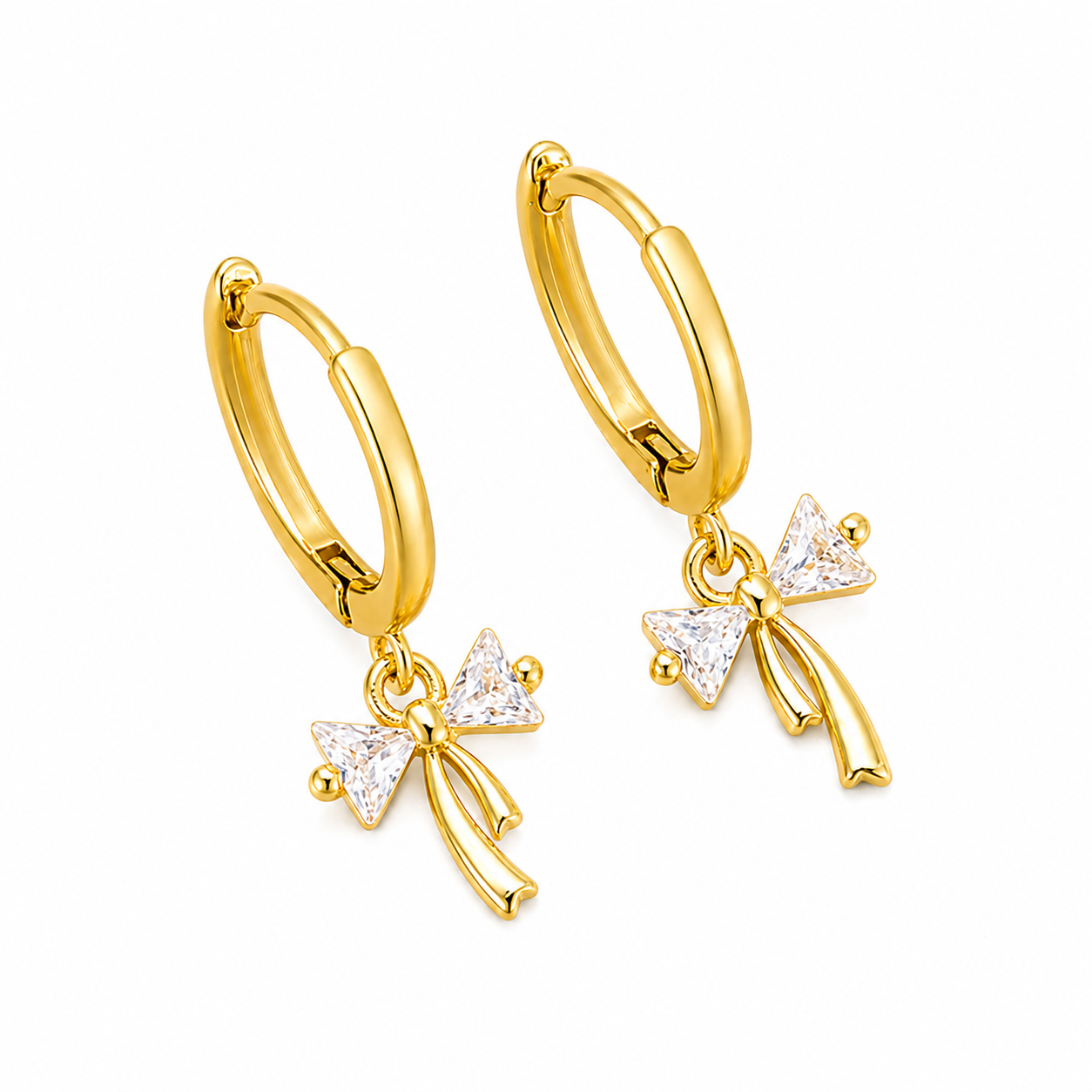 A pair of gold hoop earrings with dangling bow charms embellished with clear triangular gemstones