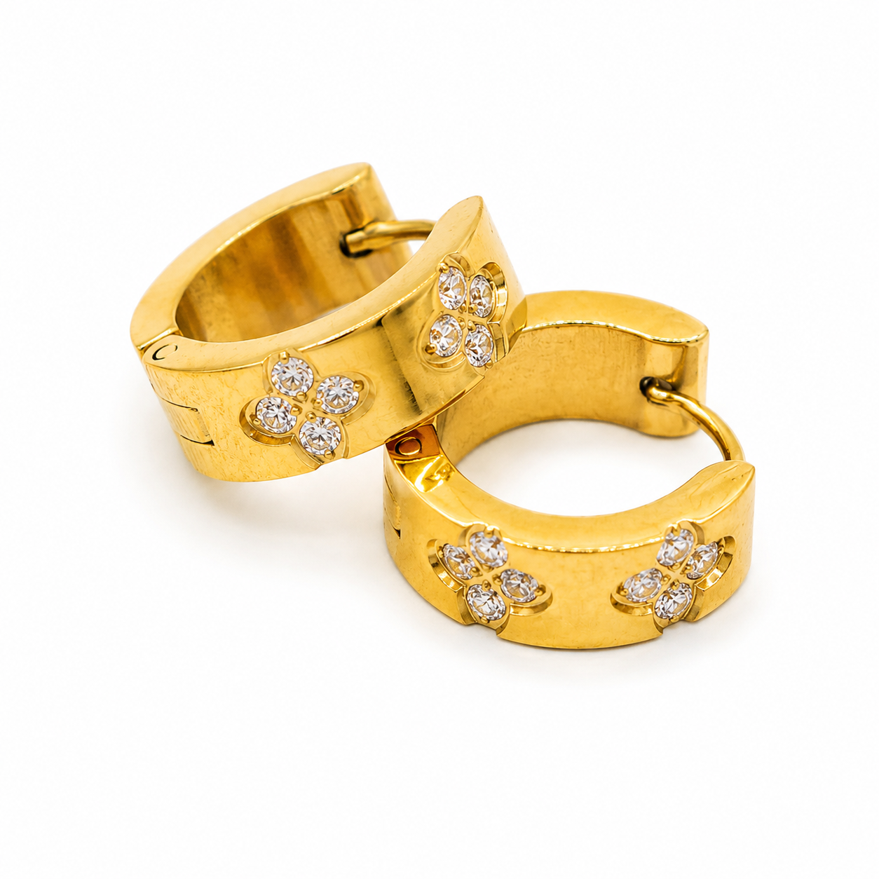 A pair of gold huggie hoop earrings decorated with four floral clusters of small clear stones on each earring