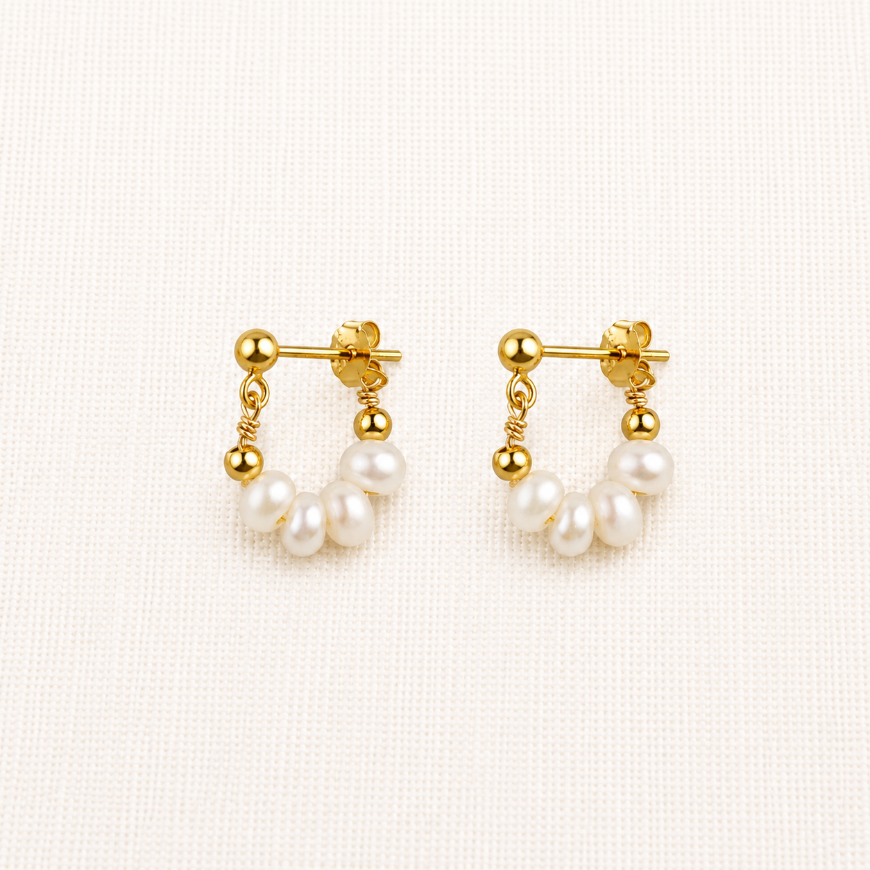 A pair of gold pearl huggies