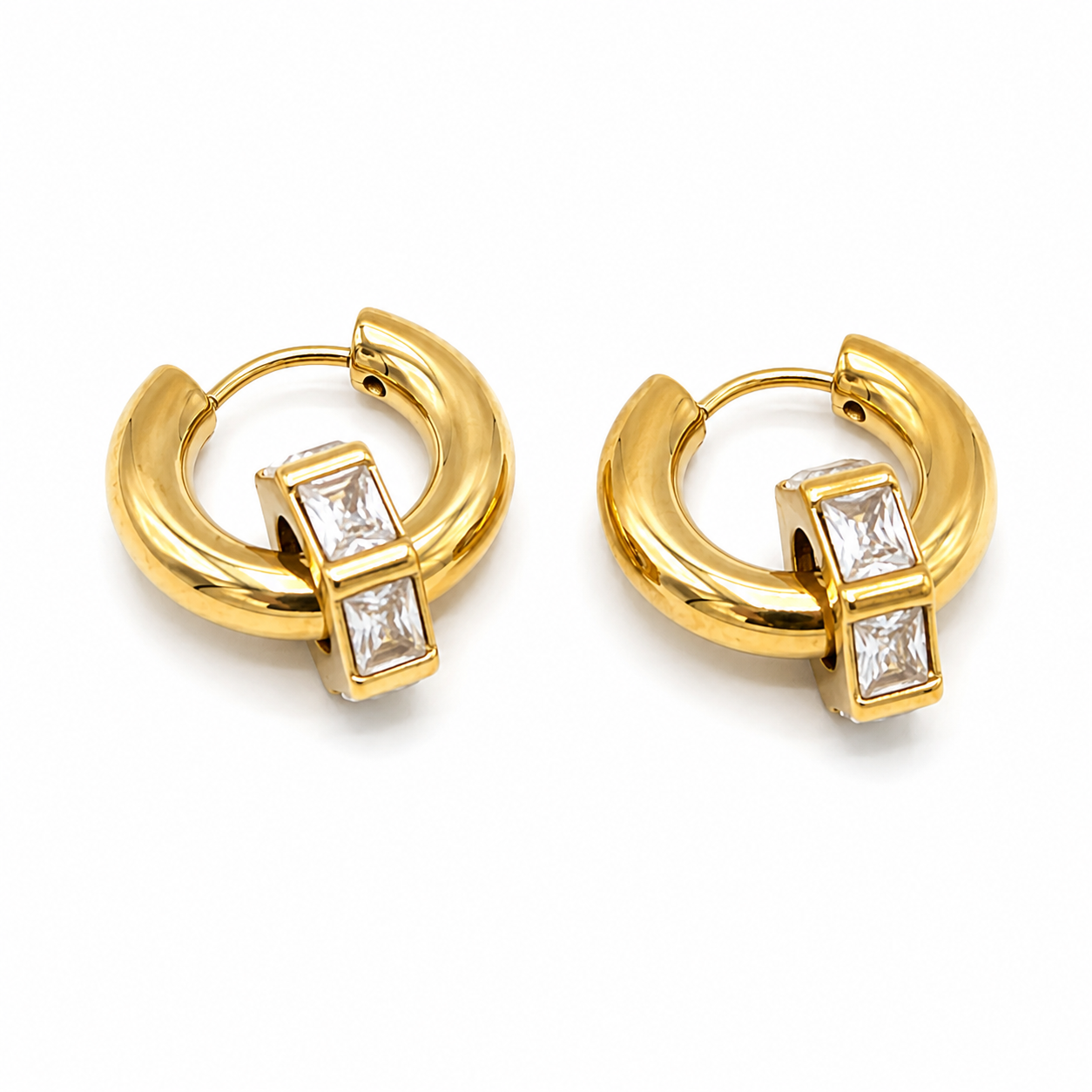 A pair of gold huggie hoop earrings with rectangular baguette-cut clear stones