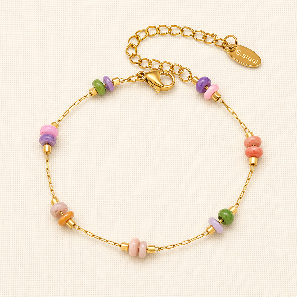A gold chain bracelet with small pastel-colored spacer beads in pink, purple, green, and orange