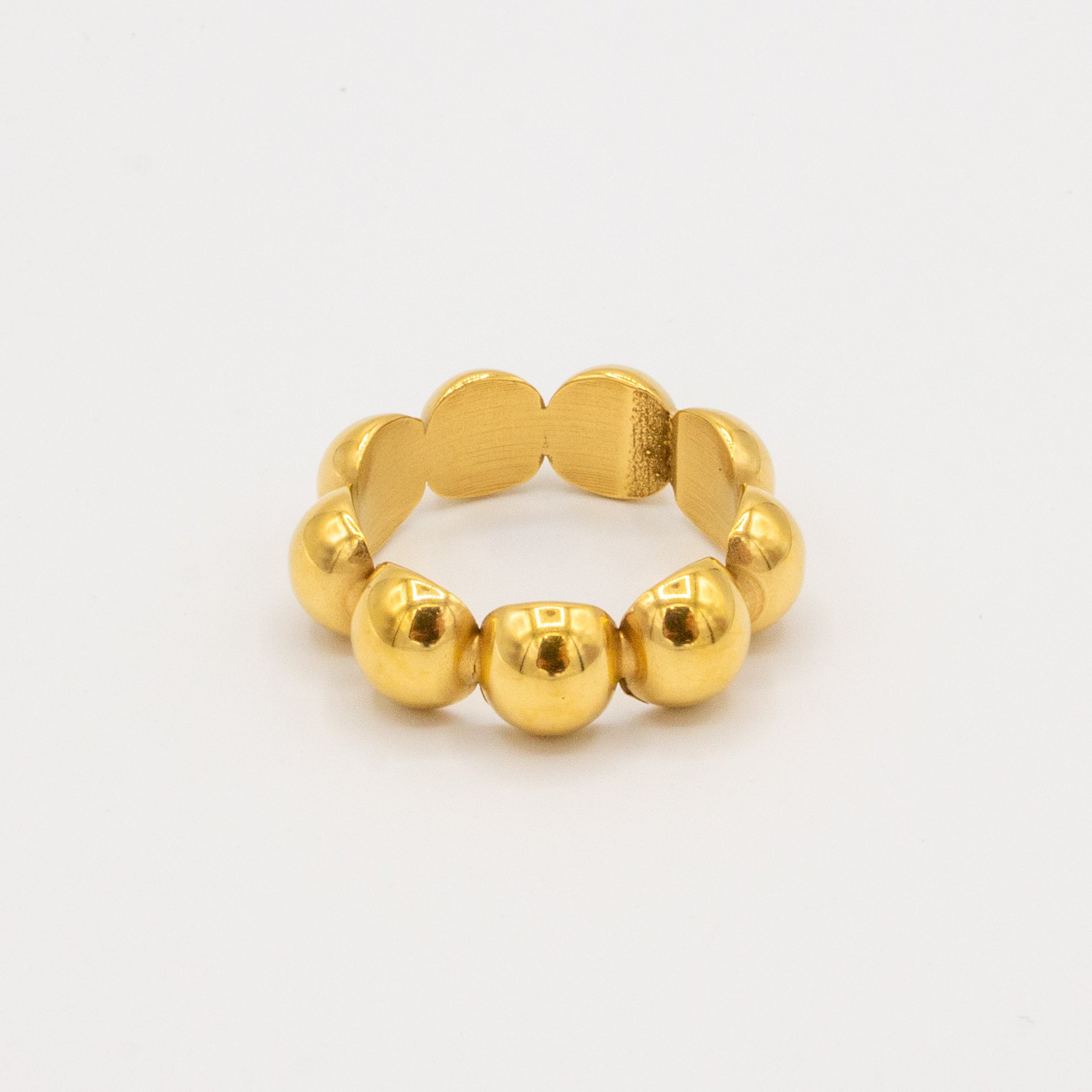 A golden orb ring with a series of rounded gold elements, possibly a wedding band or a statement piece for sensitive skin.