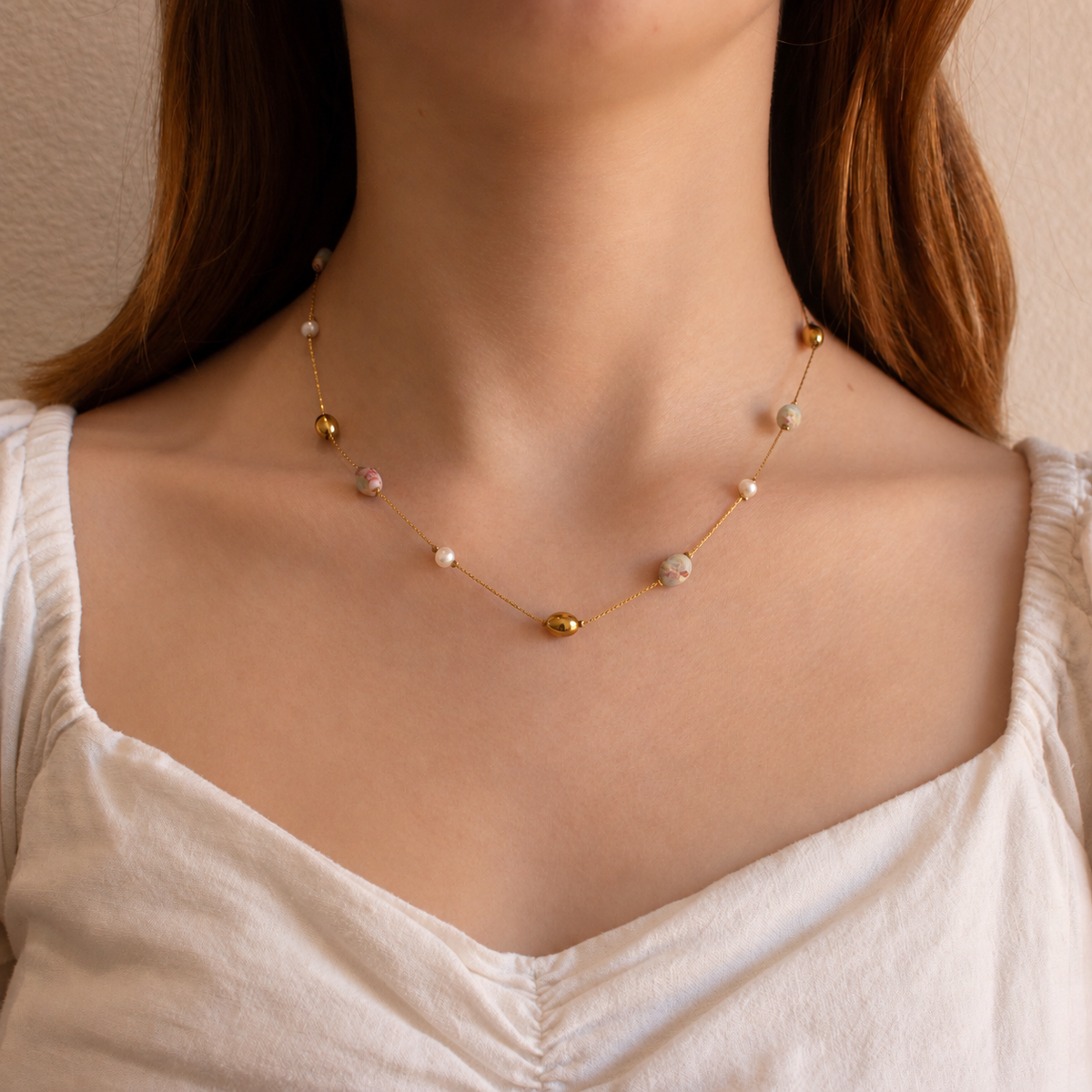 A delicate gold chain necklace with small gold beads and white pearls