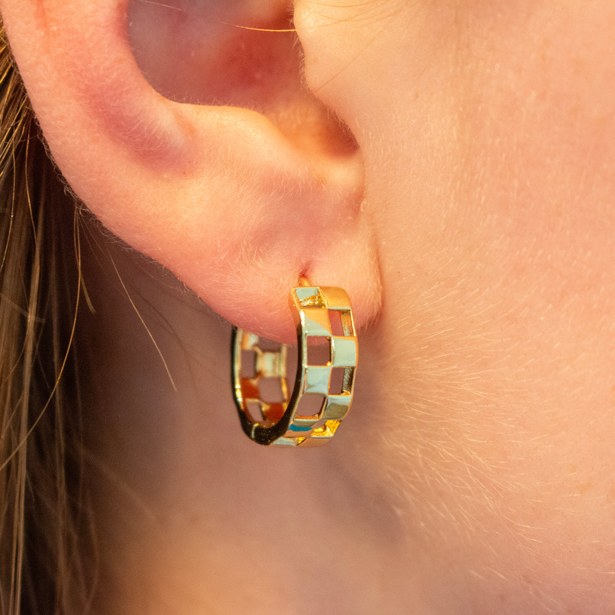 a small hoop earring with alternating gold and light blue enamel sections.