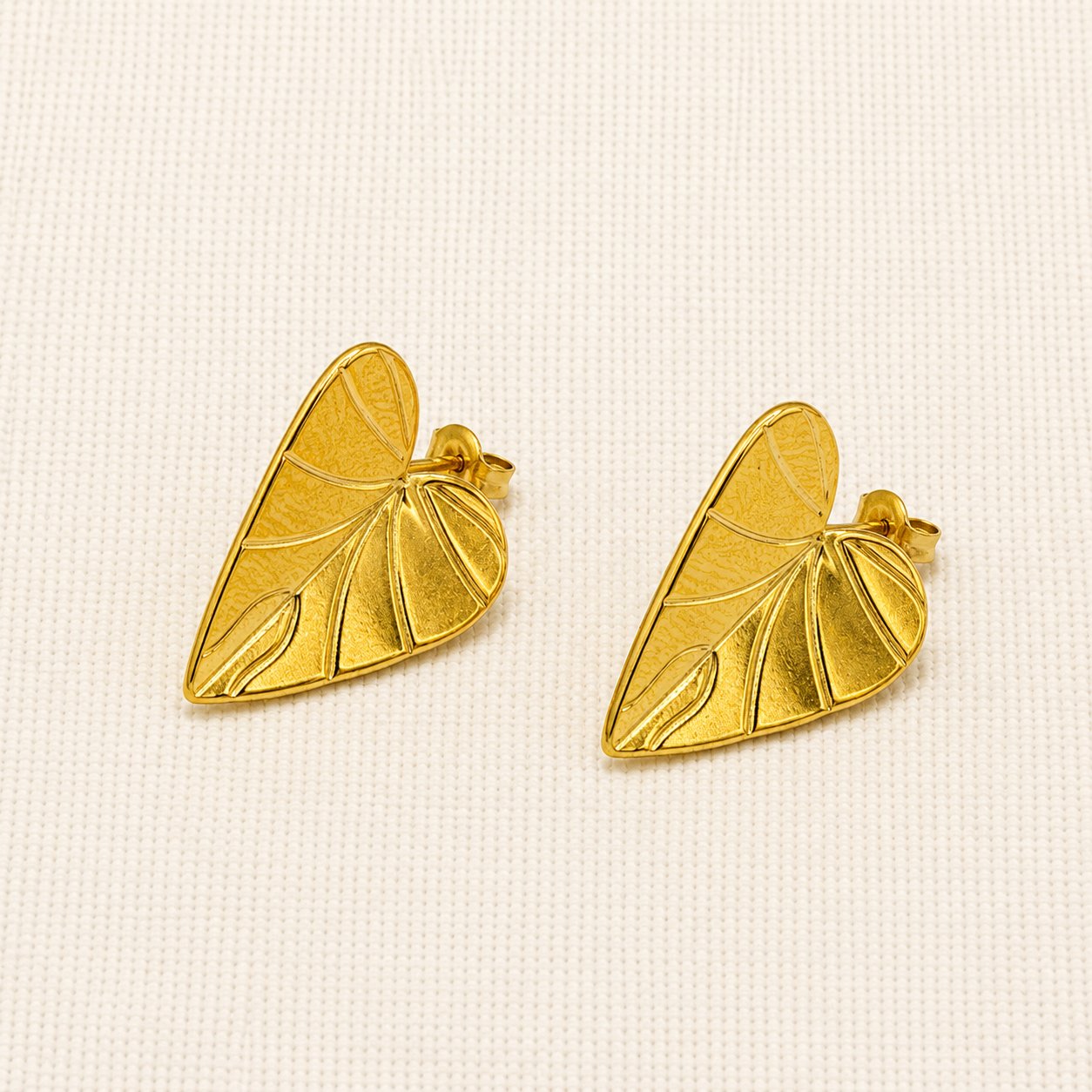 A pair of gold leaf-shaped stud earrings with textured vein details
