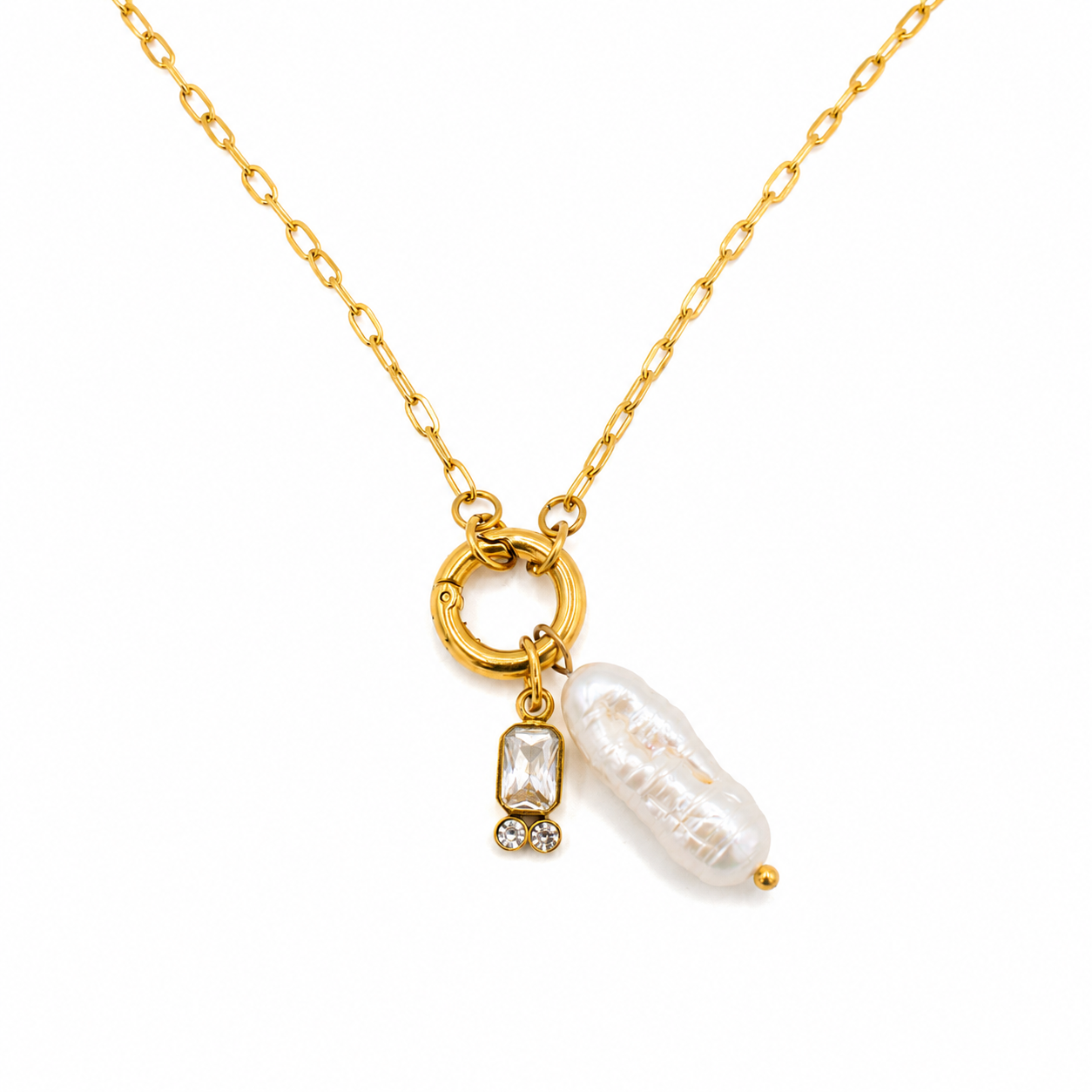 A gold chain necklace featuring a circular ring charm, a small clear rectangular gemstone with tiny clear accent stones, and a baroque-style white pearl pendant