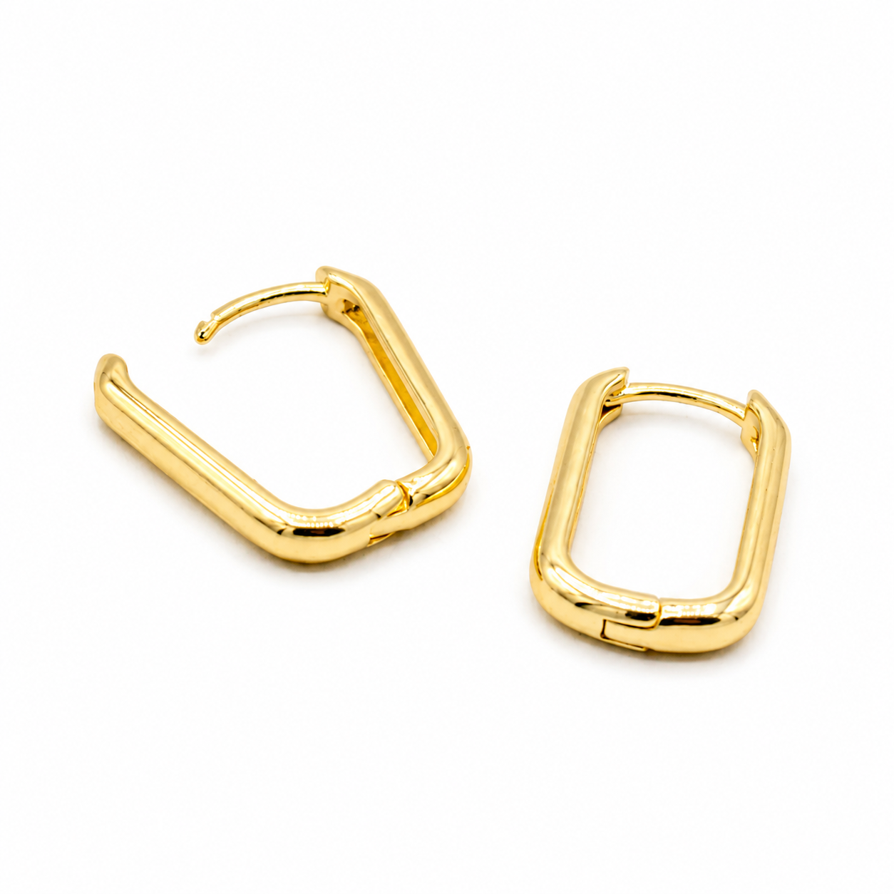 A pair of gold-toned square huggie hoop earrings with a thick, polished tubular design
