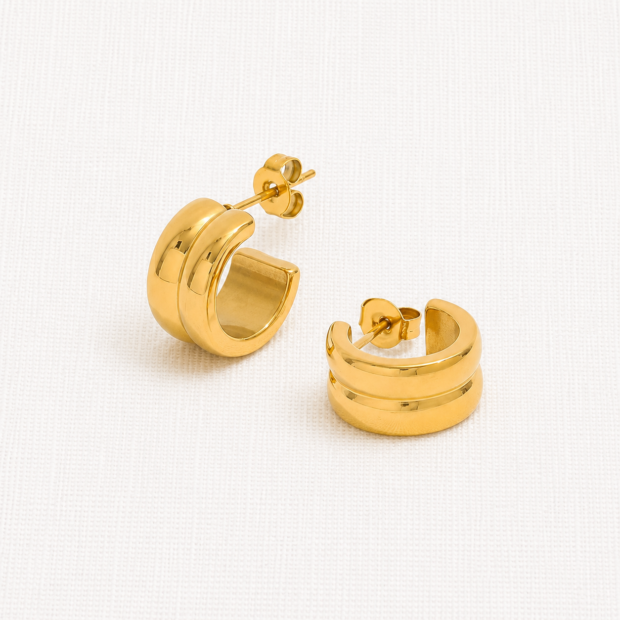 A pair of polished gold huggie hoop earrings with a thick, rounded double-band design