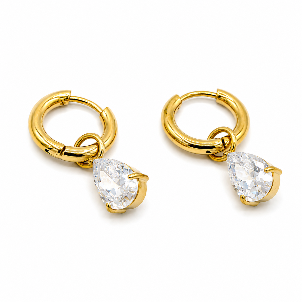 A pair of gold huggie hoop earrings with dangling teardrop-shaped clear gemstones