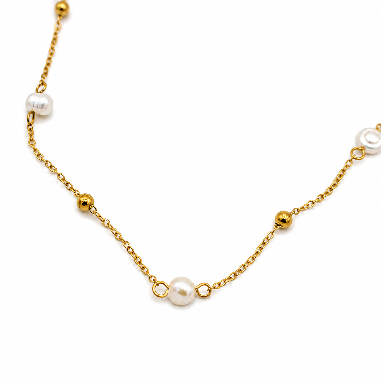 A delicate gold chain necklace featuring small gold beads and several white freshwater pearls spaced along the chain