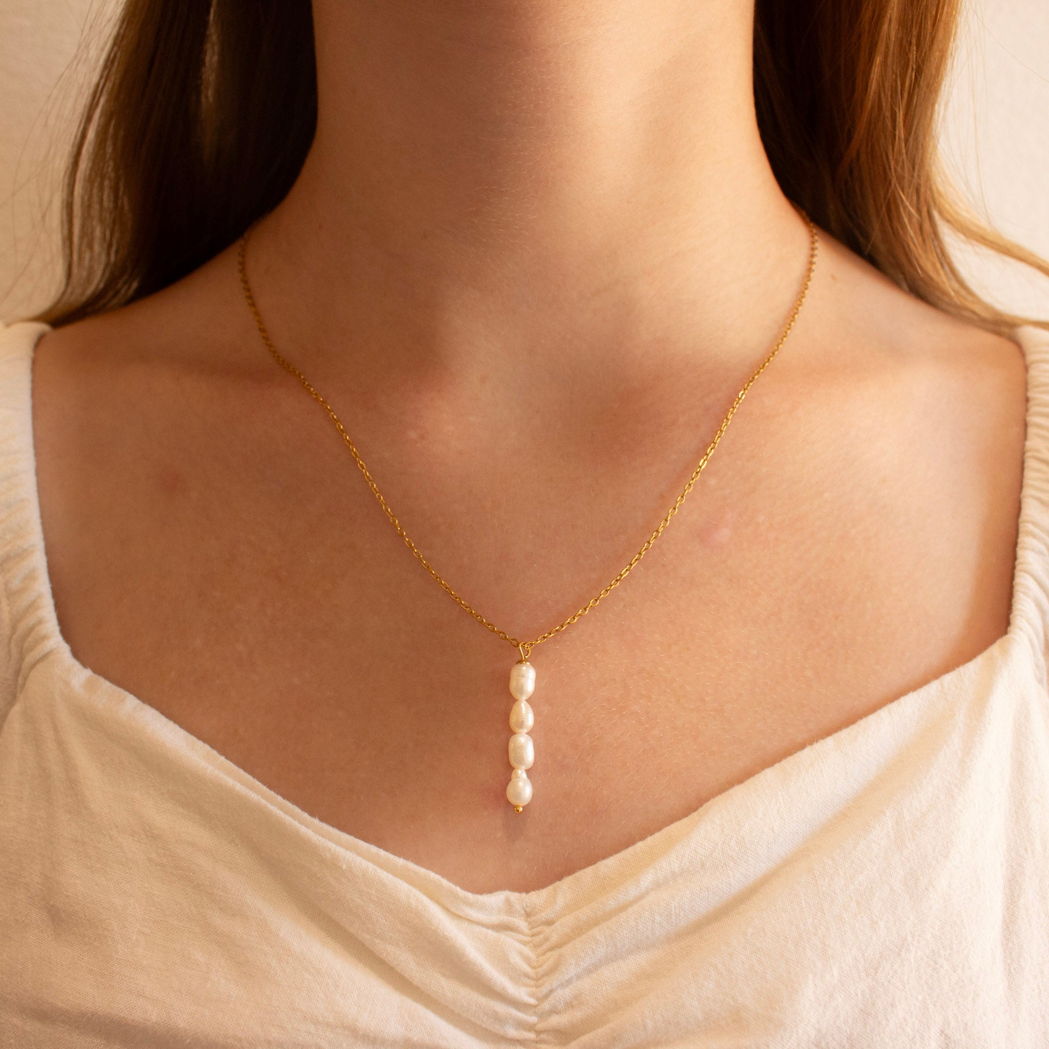 delicate gold chain necklace with a vertical drop of four white baroque pearls
