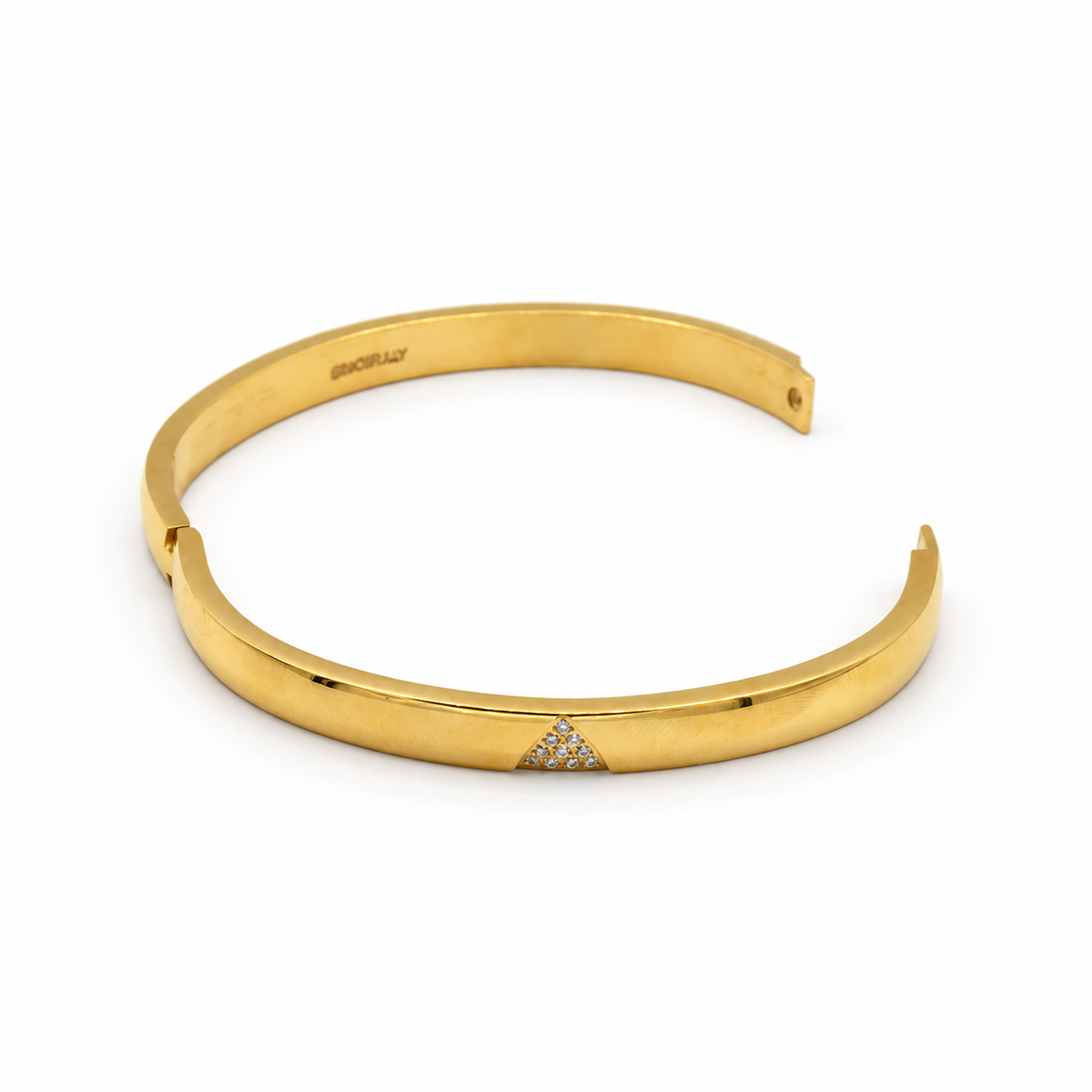 A polished yellow gold cuff bracelet with a small pavé diamond triangle accent on the front,