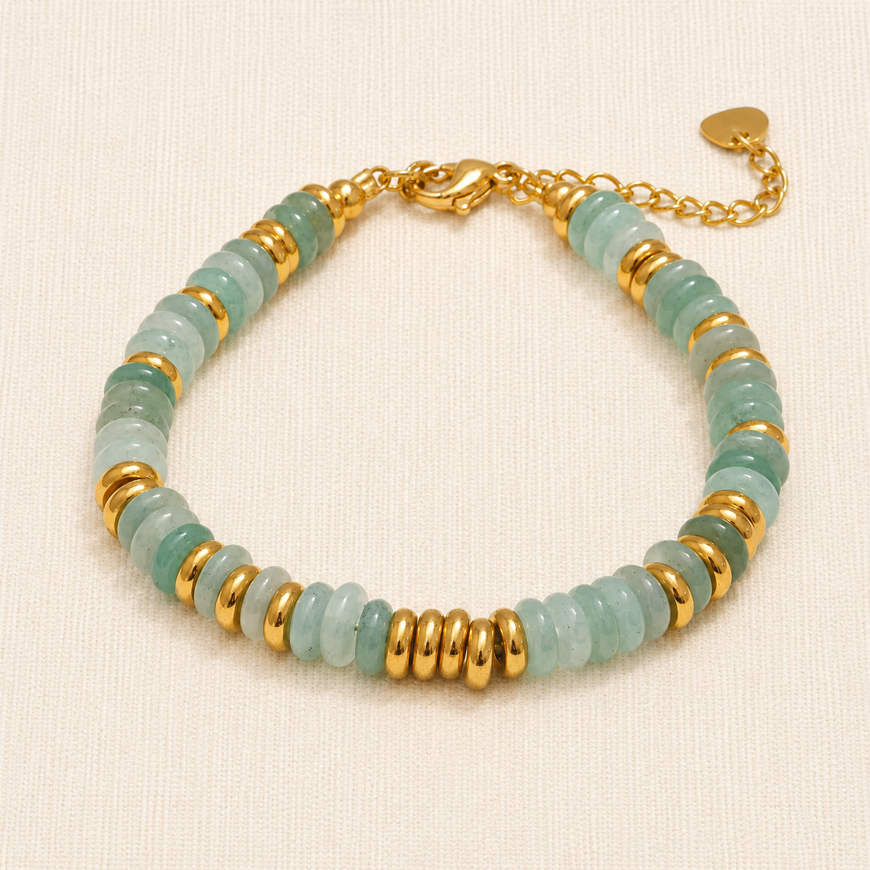 A beaded bracelet featuring light green stone discs and polished gold spacer beads