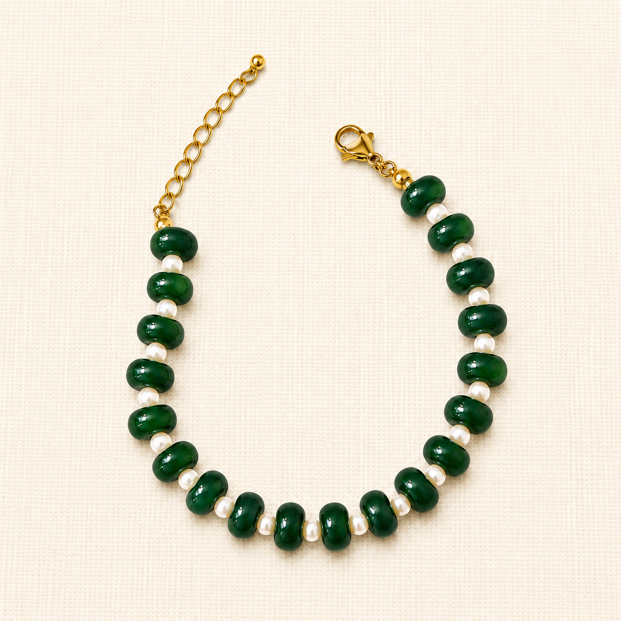 A beaded necklace featuring glossy dark green oval beads separated by small white pearl-like beads, with a gold-tone chain extender and lobster clasp