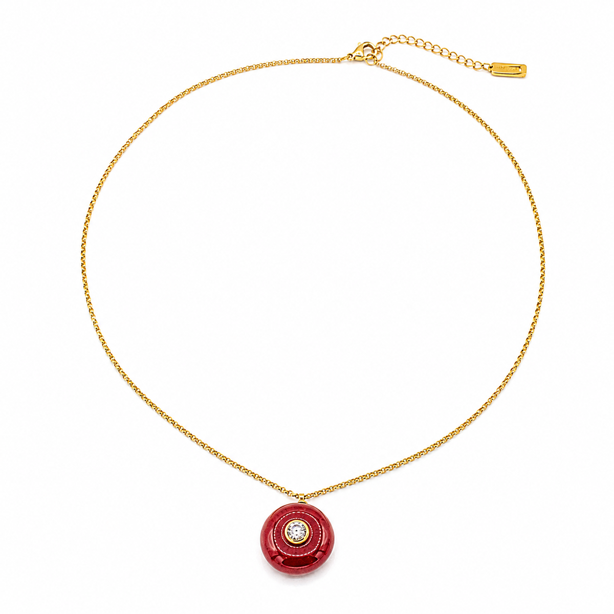A gold chain necklace with a circular red pendant featuring a central clear gemstone