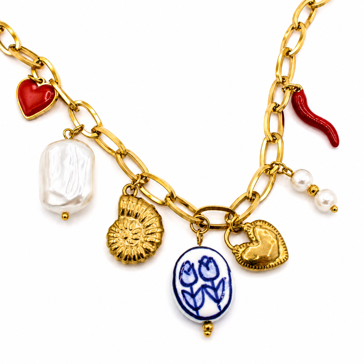 A gold chain necklace with multiple charms, including a red heart, a white baroque pearl, a gold seashell, a blue and white tulip medallion, a gold heart, and a red chili pepper charm