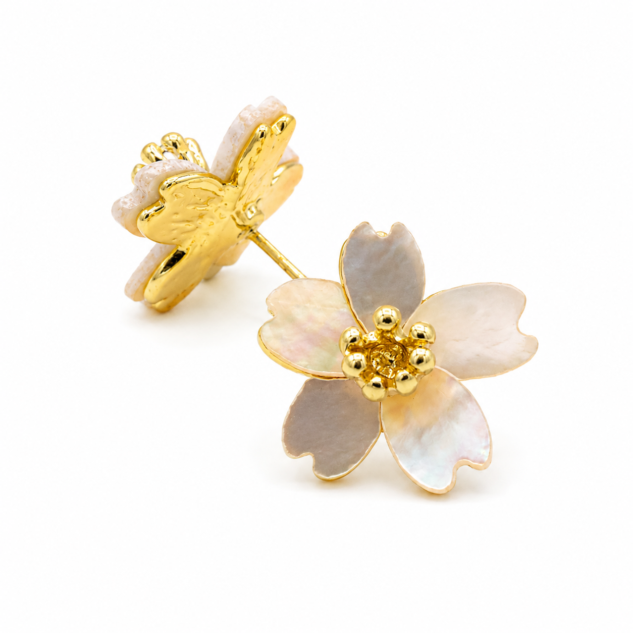 A pair of gold flower stud earrings with iridescent mother-of-pearl petals, shown on a clean white background. One earring is oriented to show the gold post and backing, while the other is angled to show the front of the flower with its gold center.