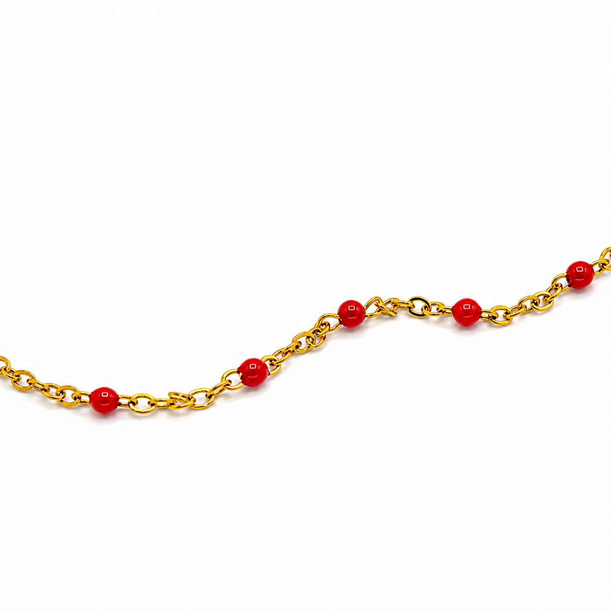 A gold chain necklace featuring evenly spaced, glossy red spherical beads