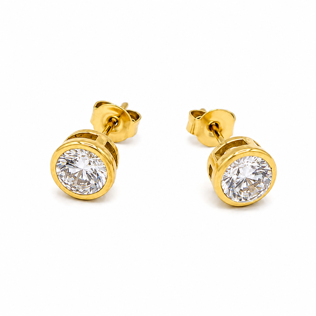 A pair of yellow gold stud earrings with round-cut clear gemstones in a bezel setting