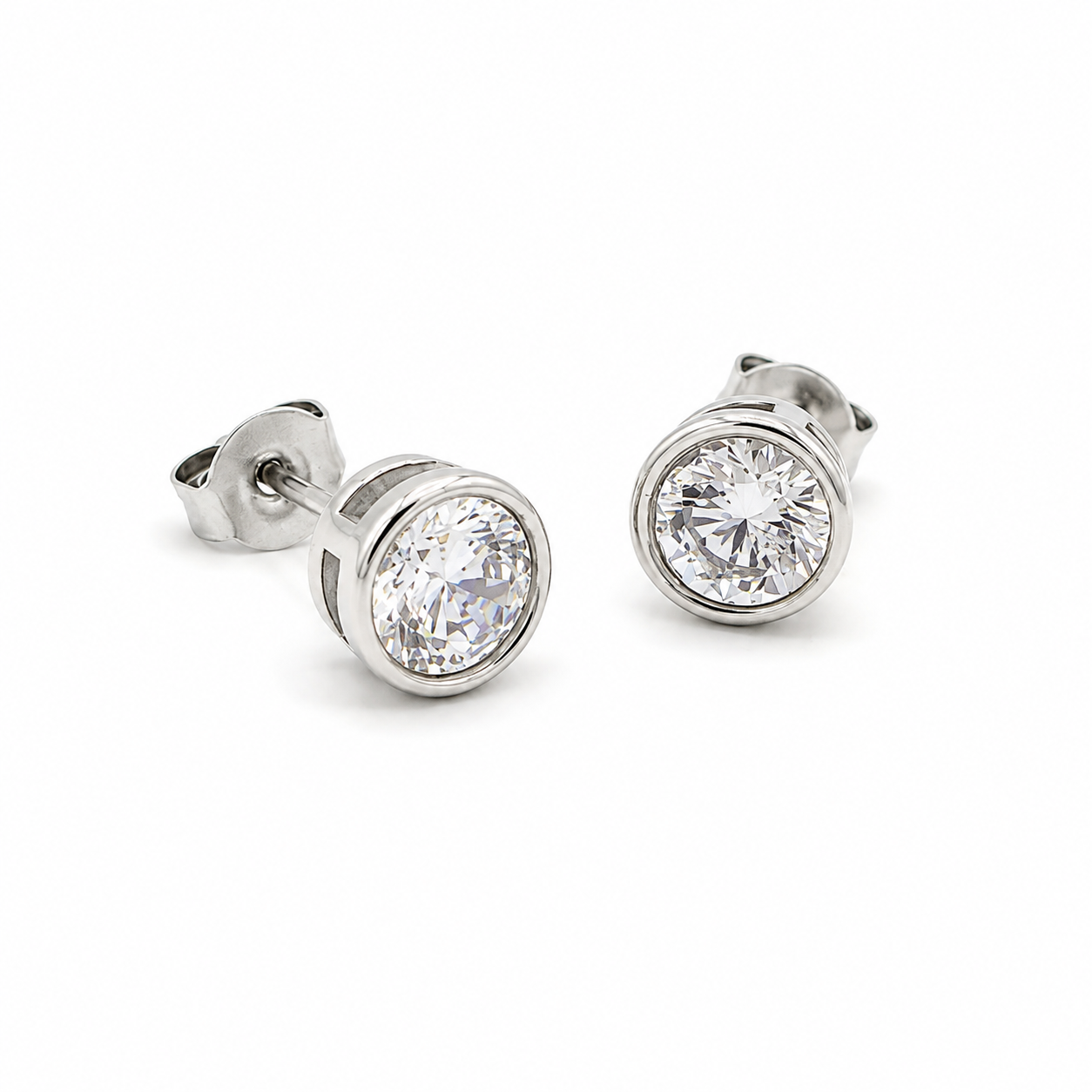 A pair of round bezel-set stud earrings in silver-tone metal with clear faceted gemstones
