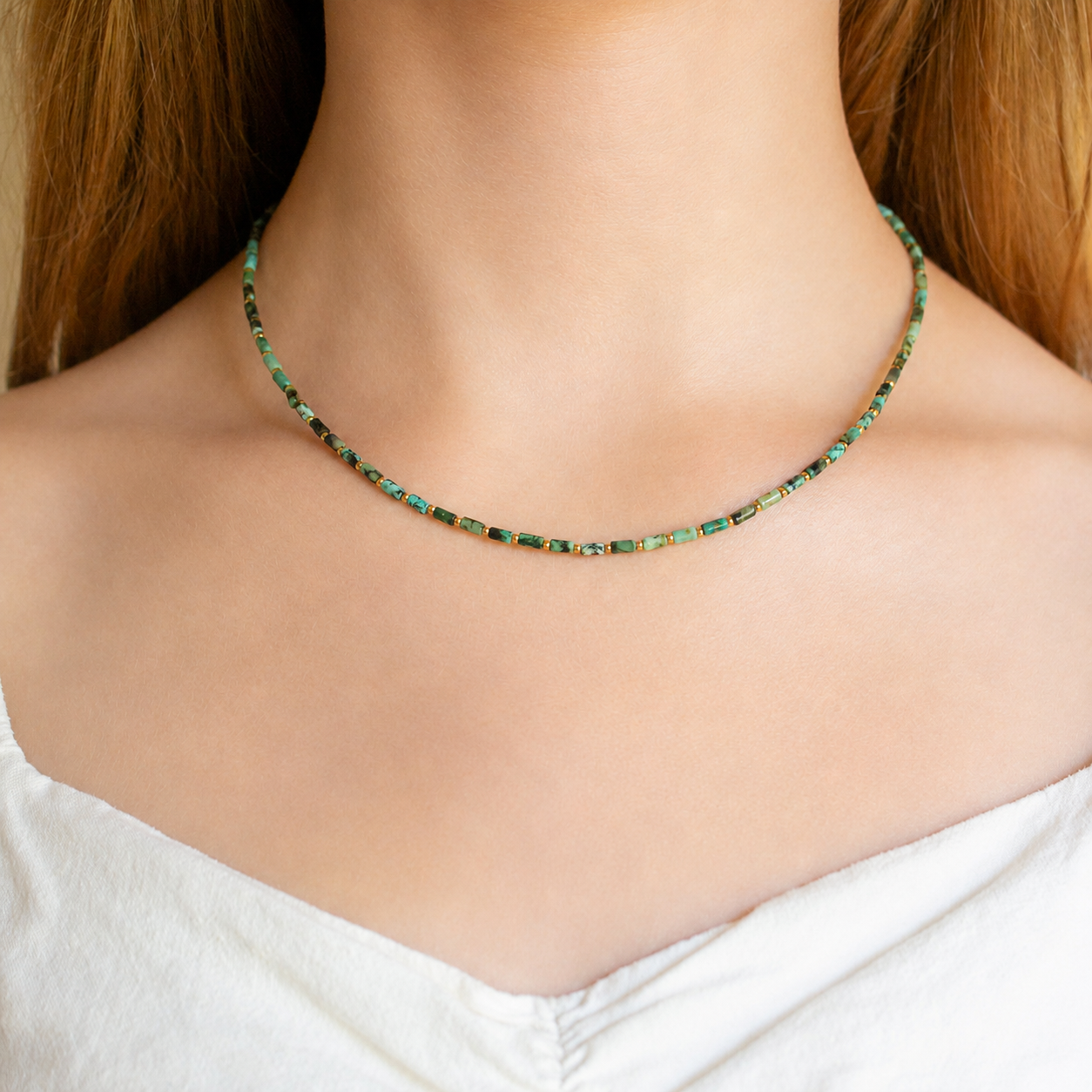 delicate beaded necklace made of small green and gold rectangular beads