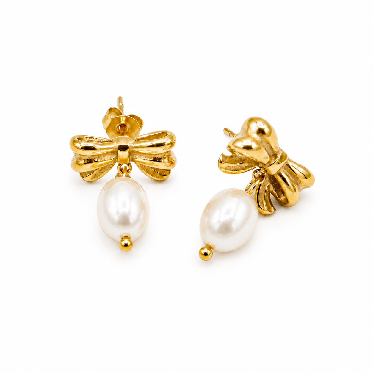 A pair of gold bow stud earrings with dangling white freshwater pearls